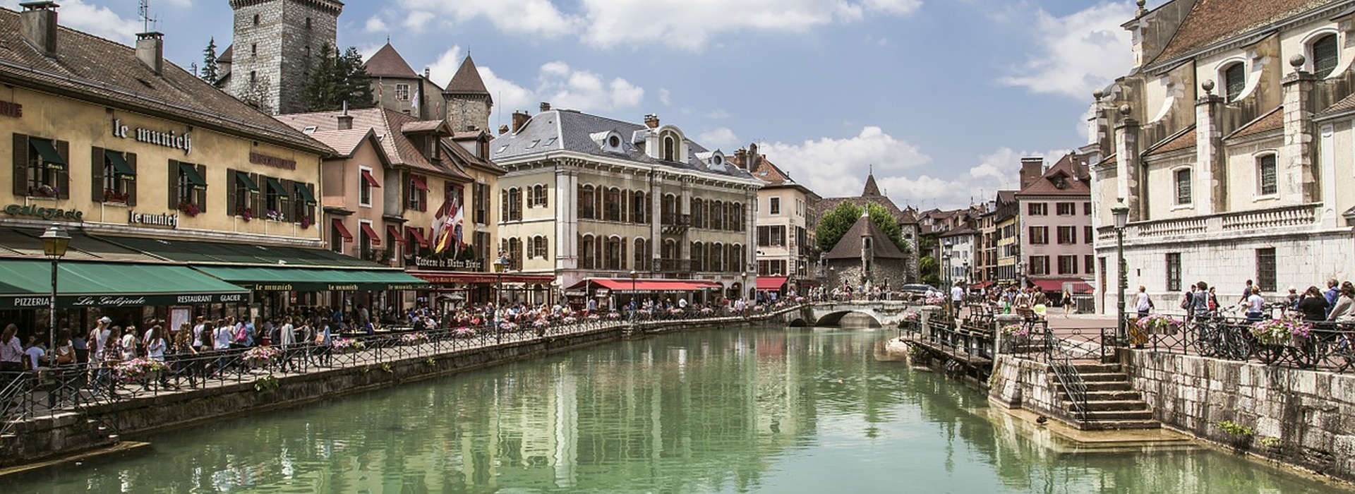 Canal in Annecy old town France with colorful buildings and people walking along the water.