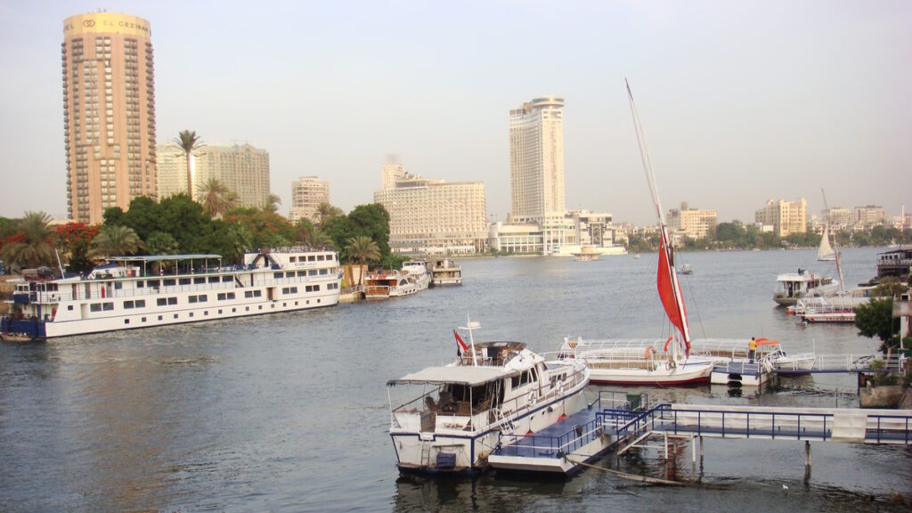 Boats on the Nile River with Cairo skyline and hotels in the background, Egypt.