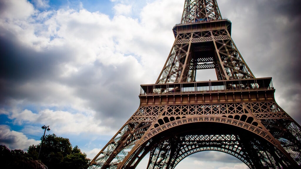 Eiffel Tower in Paris France viewed from below with sky and clouds.
