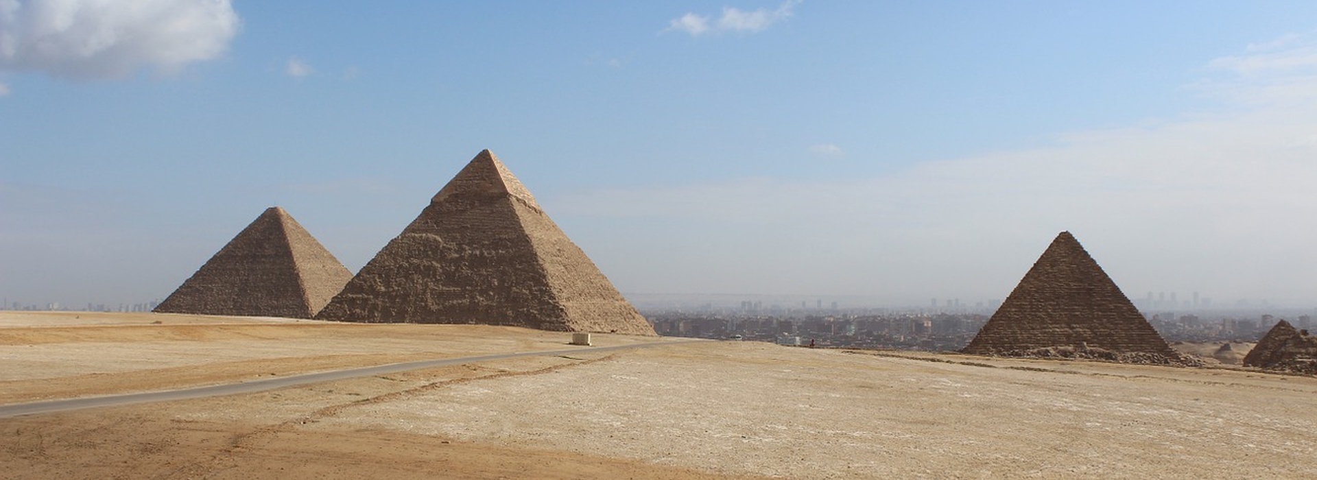 The Great Pyramids of Giza in Egypt with desert landscape and Cairo skyline in the background.