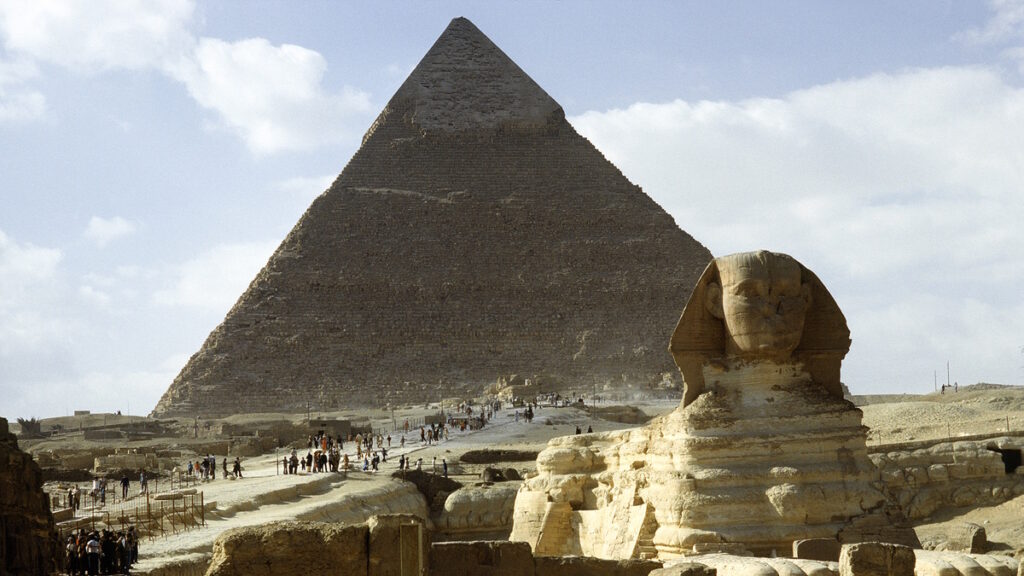Great Pyramid of Giza and the Sphinx in Egypt with tourists in the desert.