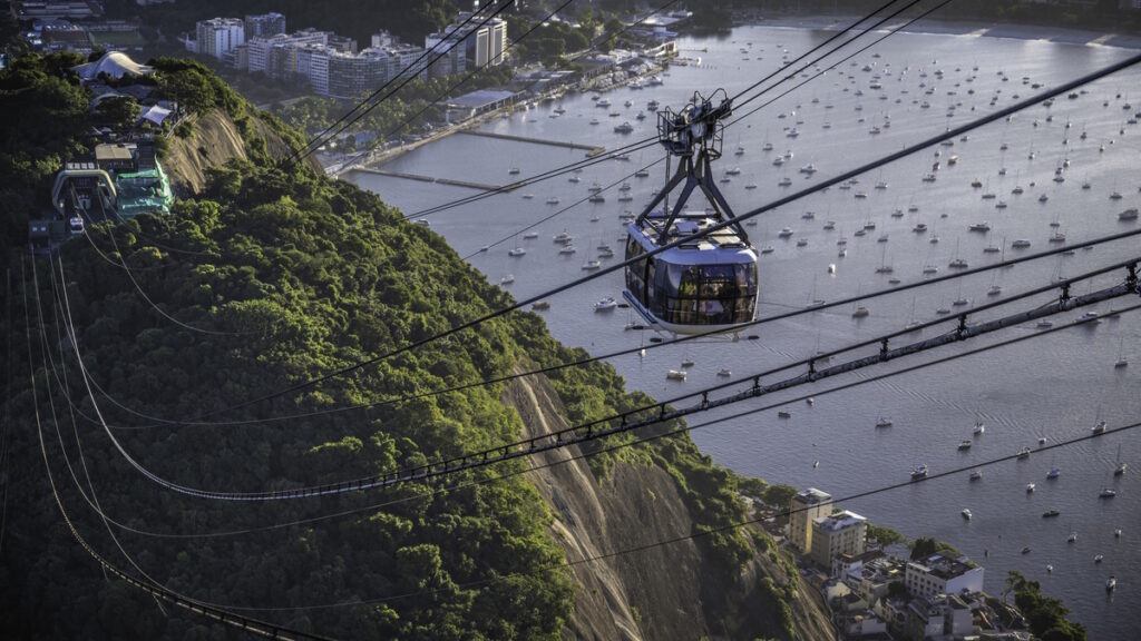 Sugarloaf Mountain cable car overlooking Rio de Janeiro harbor with boats and coastline in Brazil.
