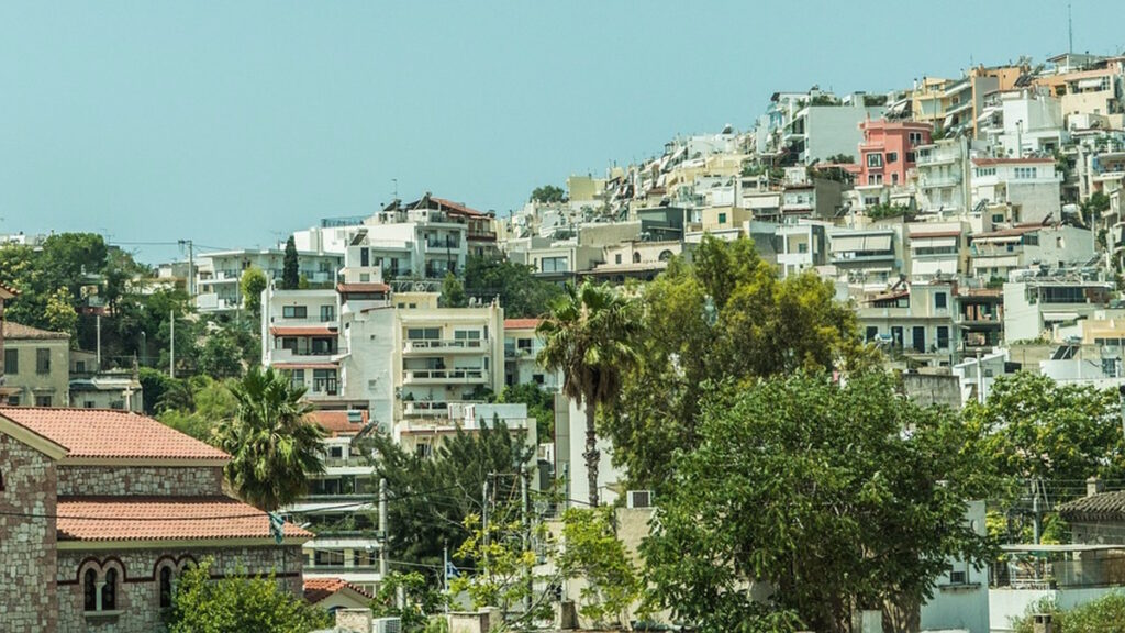 Cityscape of Athens Greece with hillside homes and urban buildings surrounded by greenery.